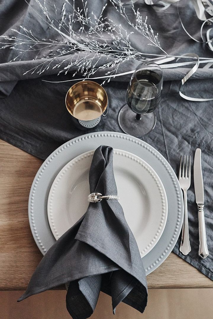 Nyårsdukning i gråblå toner och detaljer i silver som servettring från Skultuna och vinglas i rostfritt stål från Stelton. 
