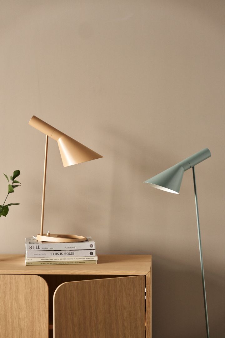 AJ-lamporna av Arne Jacobsen finns i flera olika modeller och färger, här en bordslampa i färgen warm beige tillsammans med golvlampa i färgen dusty blue.