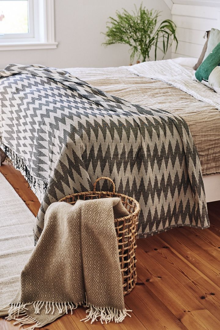 Ett sovrum inrett i skandinavisk stil med mjuka textilier och kuddar i beigea nyanser är en perfekt plats för frukost i sängen. Här ser du Salt ullpläd från Scandi Living i Ernst flätade korg.