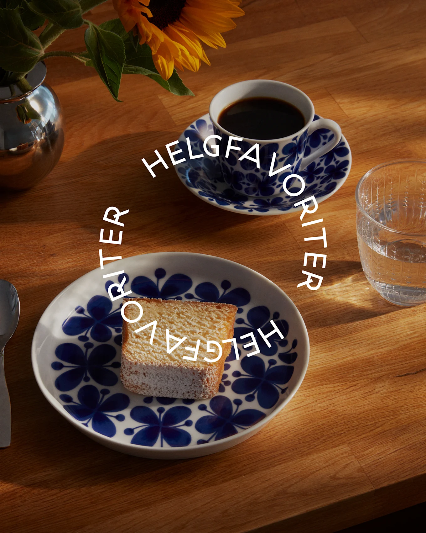 En kaffekopp, ett glas vatten och en tårta på ett fat med blåvitt mönster, med texten 'HELGFAVORITER'.