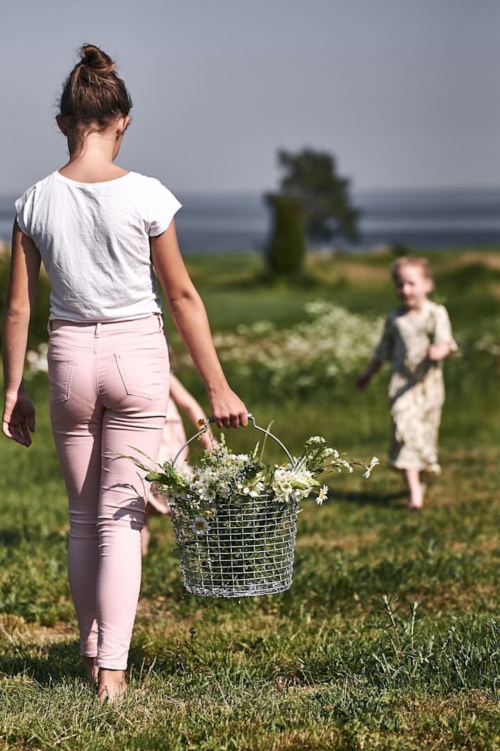 Barnen plockar vilda blommor på ängen för att skapa blomsterarrangemang på trädgårdsfesten. 