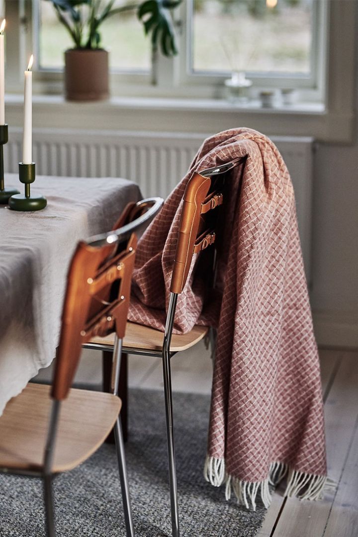 Rosa ullpläd från Scandi Living vilar på brun matstol från Design House Stockholm i en retroinspirerad matplats.