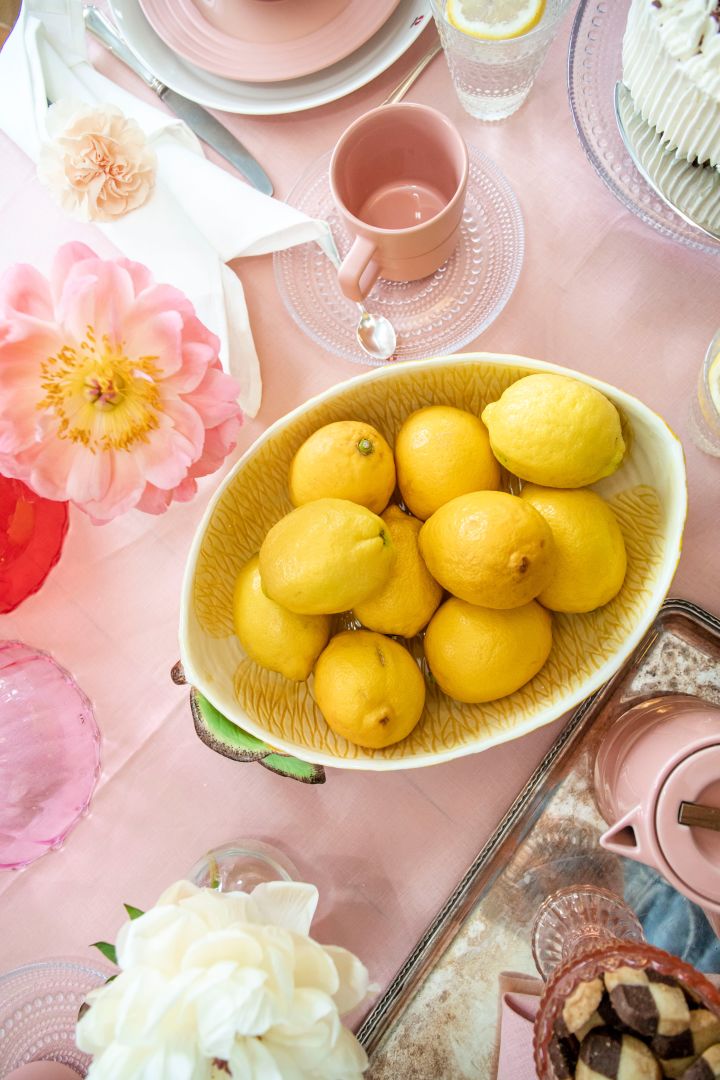 En rosa, vit och gul dukning med lekfulla detaljer och stor skål med citroner i.