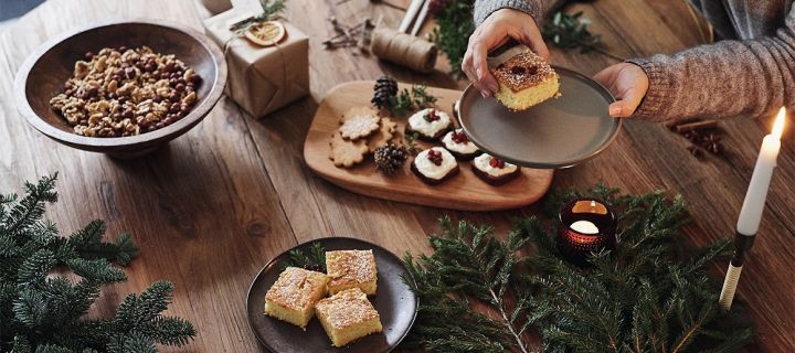 Adventsmys med julkakor som mjuk pepparkaka och saffranskaka på ett bord med granris och levande ljus tända.