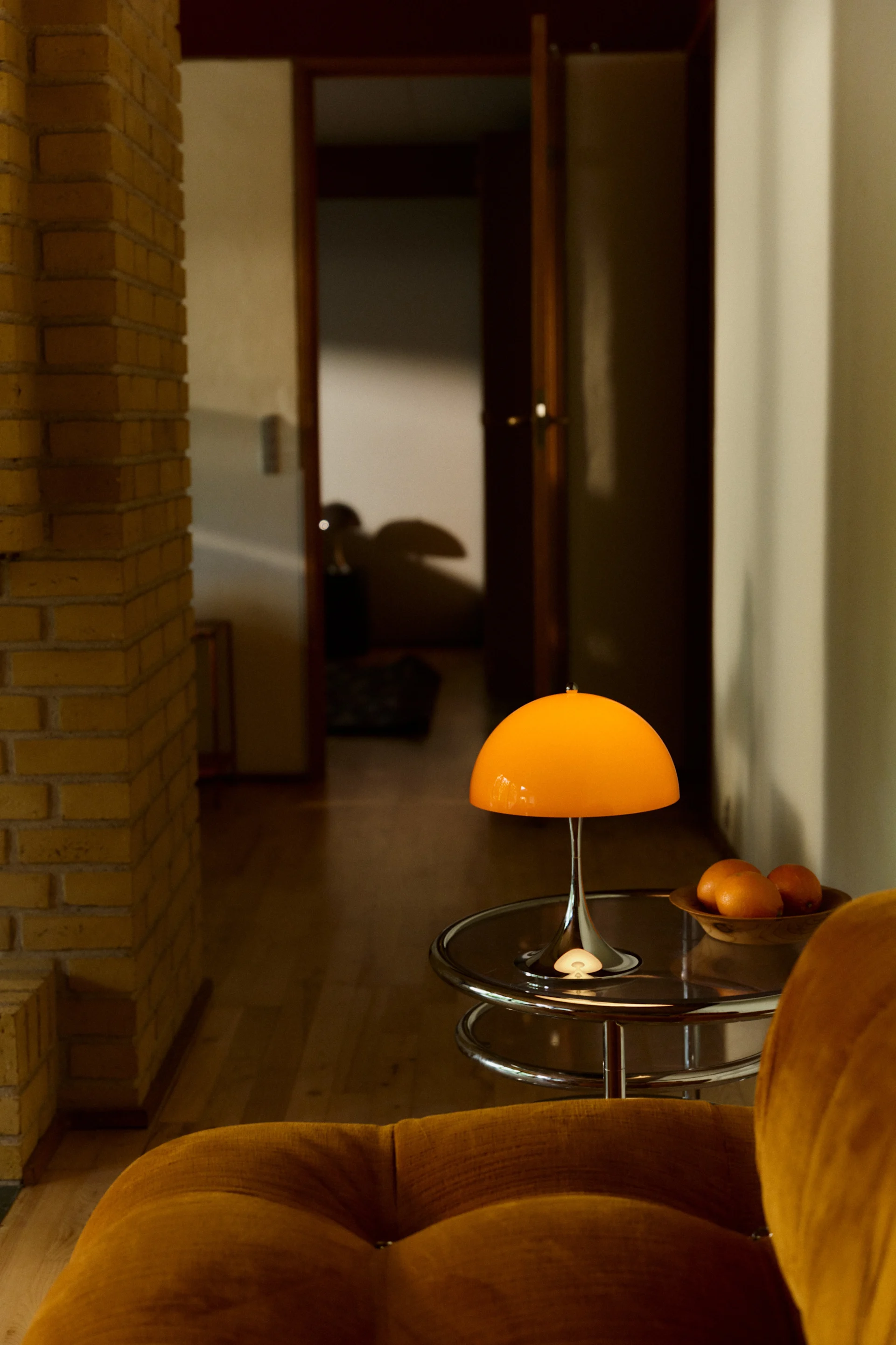 Panthella 250 uppladdningsbar lampa står på ett krom-sidobord och lyser.