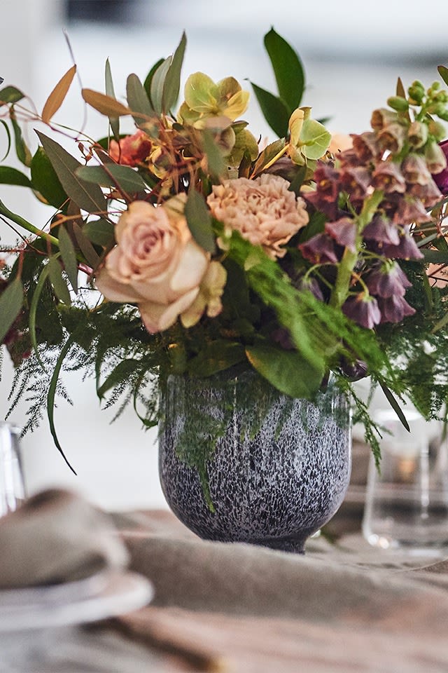 En spretig vårbukett i pastellfärger huserar i blomkruka från Kähler och förskönar denna festdukning. 