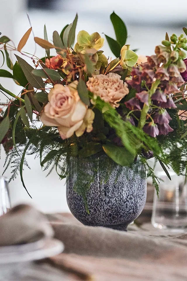 En spretig vårbukett i pastellfärger huserar i blomkruka från Kähler och förskönar denna festdukning.