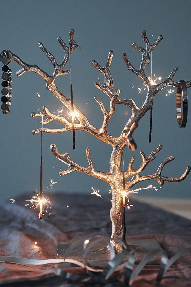 Tressa smyckesträd med tomtebloss hängandes i den blir en festlig bordsdekoration på en nyårsdukning. 