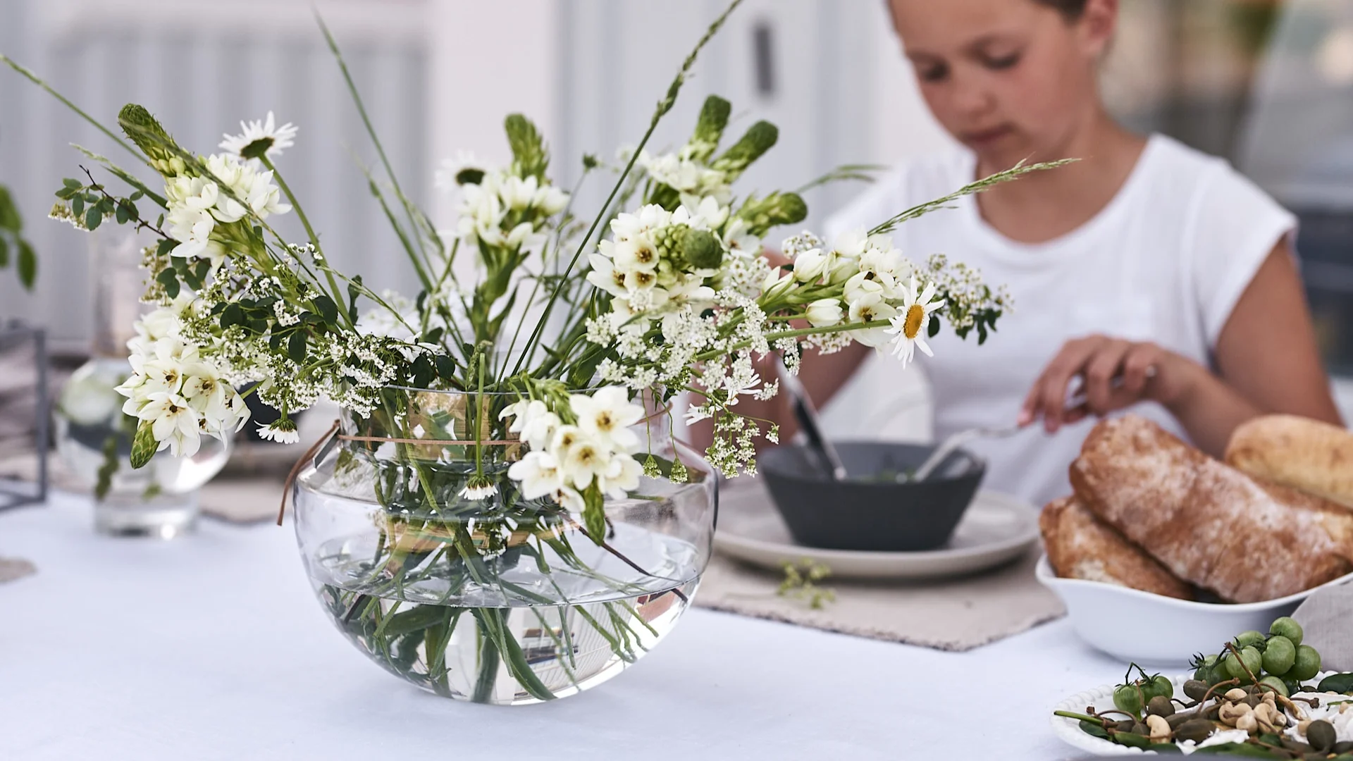 Ett fång med vilda blommor huserar i vid glasvas från ERNST på sommarlunchen och sprider härlig stämning.