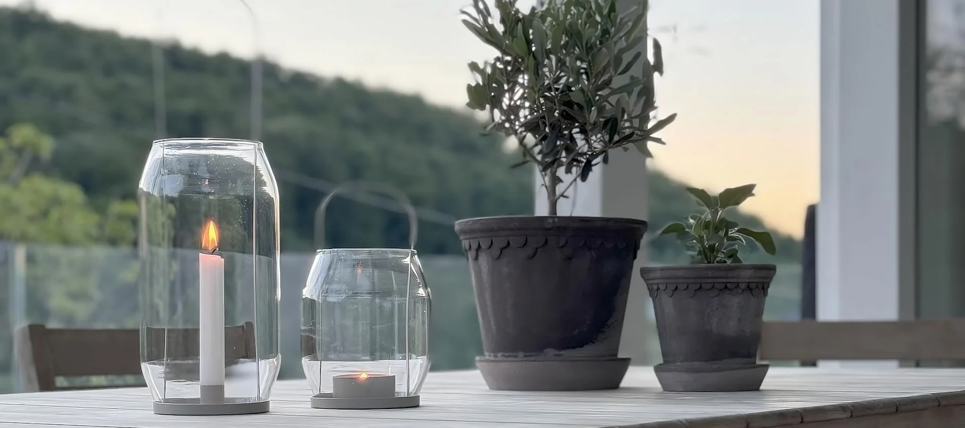 Två blomkrukor från Bergs Potter i Köpenhamn står på ett bord bredvid två Ernst-lyktor på @zuhauseligs terrass.