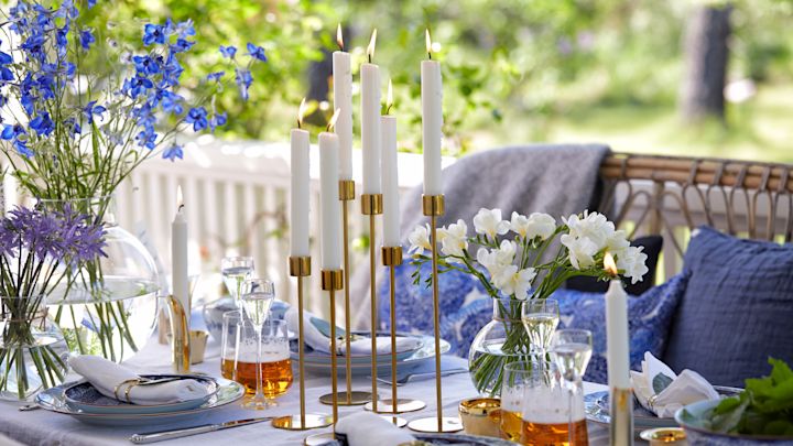Midsommardukning med ljusstakar i mässing från Cooee Design i grupp på bordet och blåvitt porslin. 