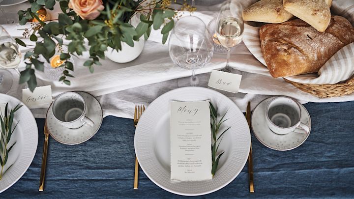 En enkel festdukning i blåvitt med Swedish Grace servis från Rörstrand, guldbestick och eleganta vinglas på en böljande blå 