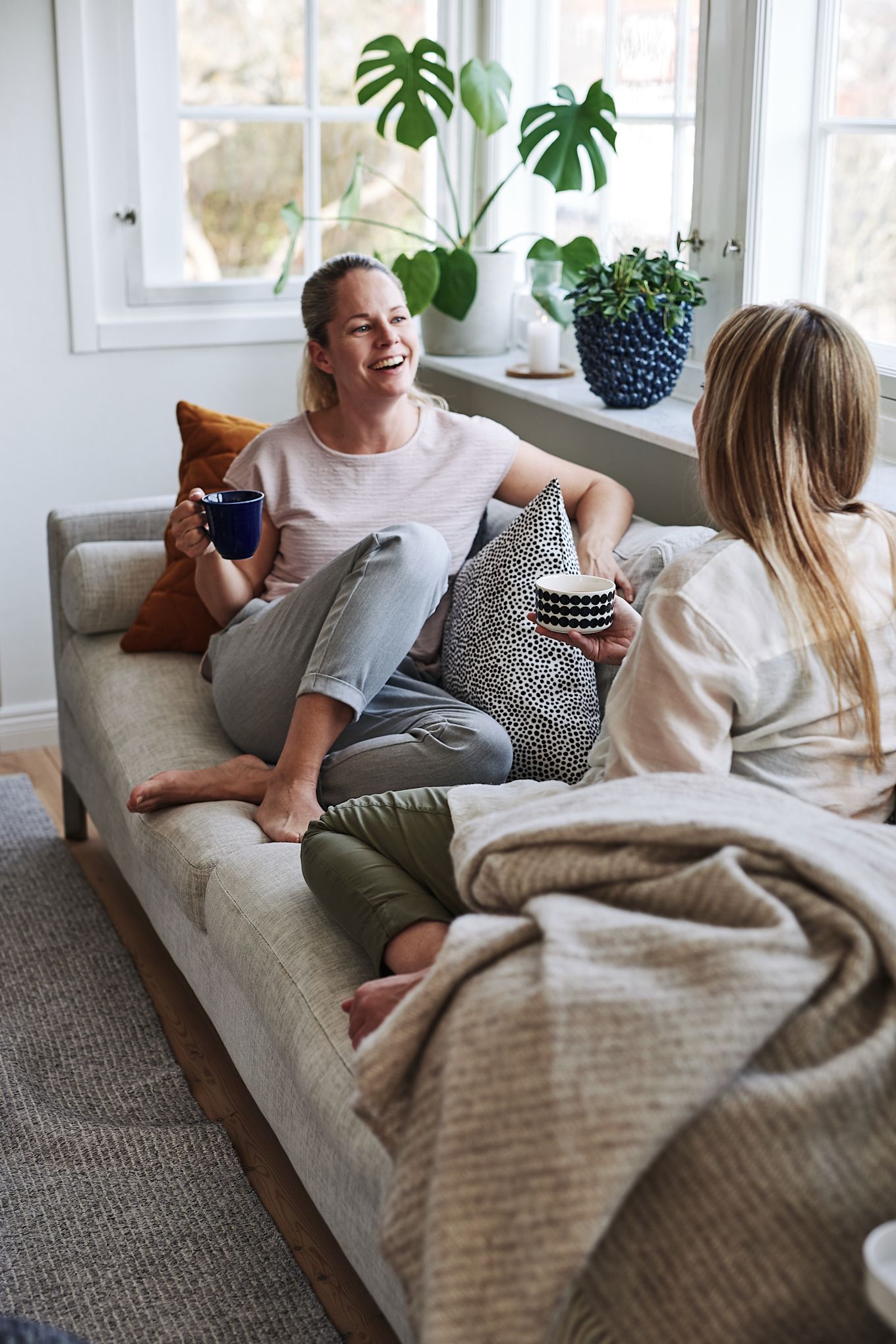 Skapa ett feng shui-vardagsrum genom att inreda socialt med hjälp av att skapa fler sittplatser. Här sitter två personer och pratar i soffan.