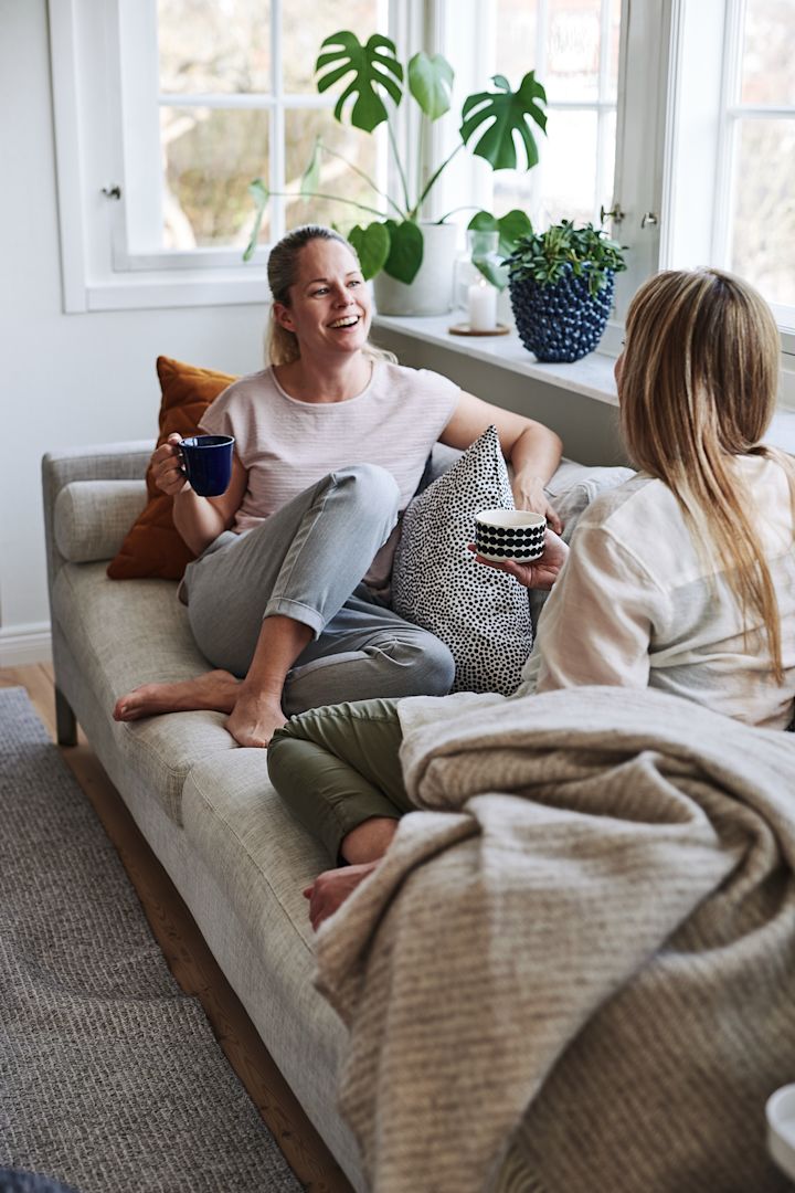 Skapa ett feng shui-vardagsrum genom att inreda socialt med hjälp av att skapa fler sittplatser. Här sitter två personer och pratar i soffan.