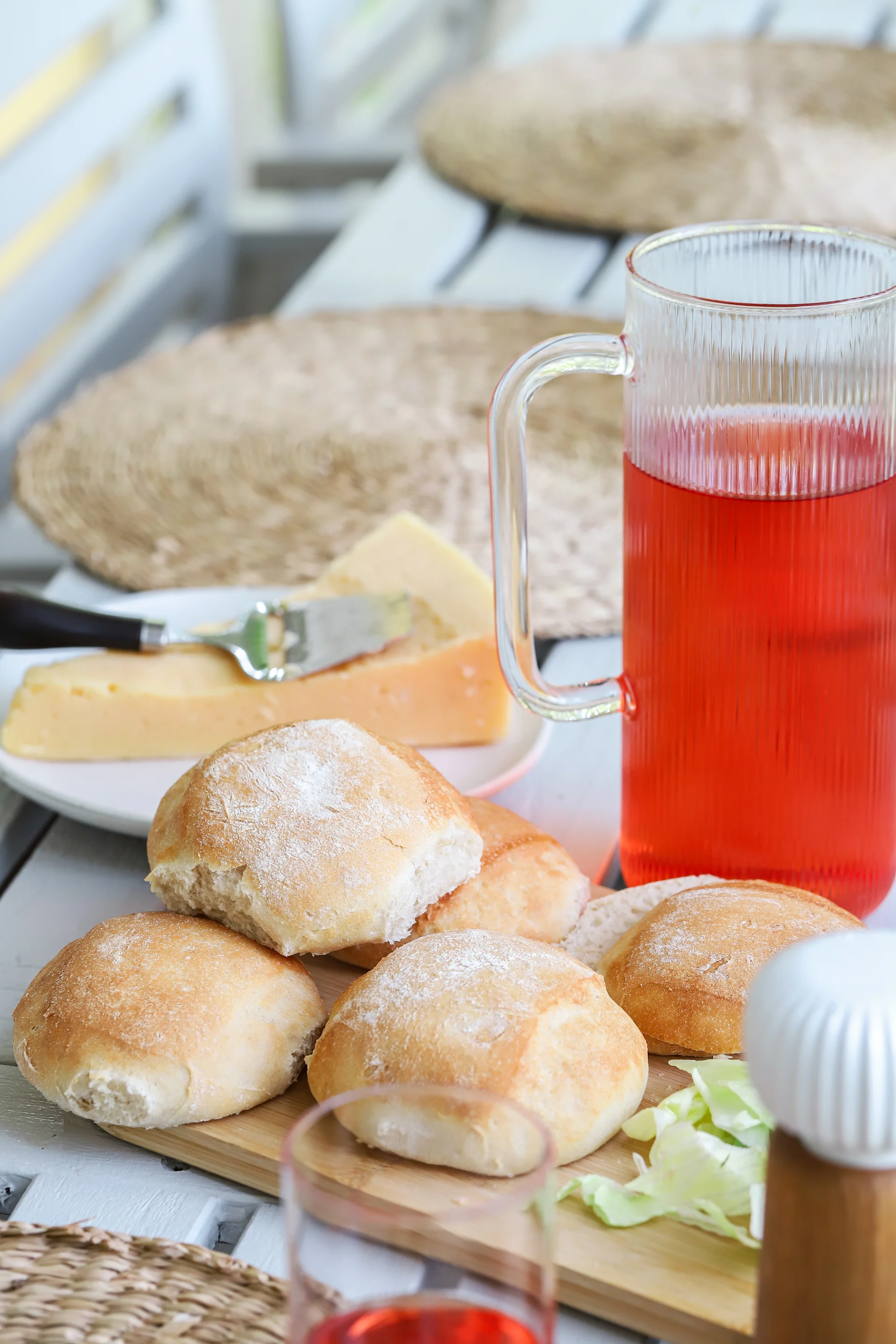 Bild som visar nybakade kalljästa frallor, staplade på Nature skärbräda i bambu från Sagaform. I bakgrunden skymtar Saga karaff och dricksglas.