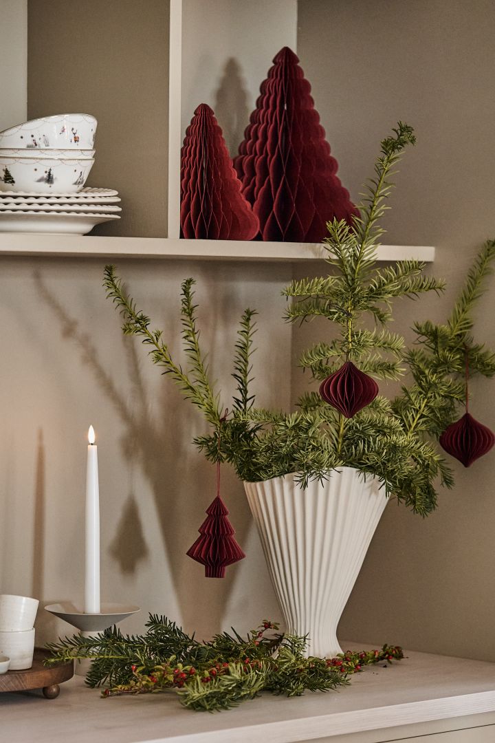Pynta en vas såsom Fountain vas från ferm LIVING med granris dekoration för att skapa julstämning i hemmet tillsammans med julhängen från Scandi Living.