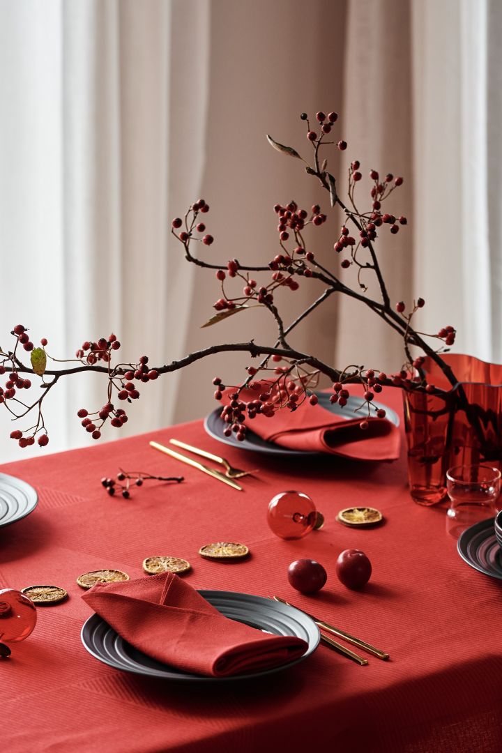 Återskapa en traditionell röd juldukning 2021 från NJRD - här ser du en elegant gren med rönnbär i en röd Alvar Aalto vas från Iittala.