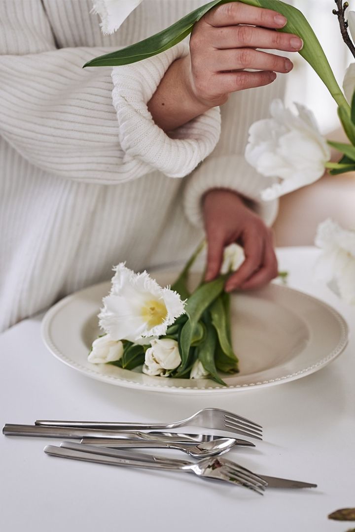 Vitt serveringsfat och bestick från Scandi Living varpå tulpaner ligger på fatet i förberedelse för en vacker vårdukning. 