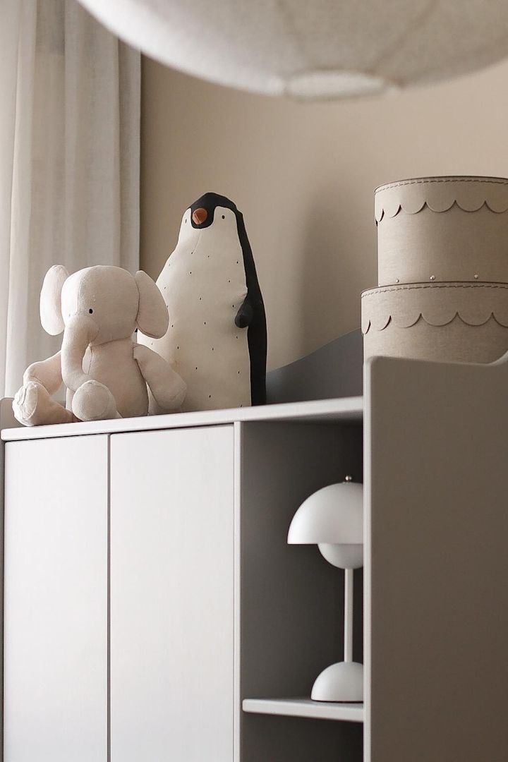 En portabel lampa som FlowerPot VP9 i vitt från &Tradition tillsammans med en nalle i bokhylla hemma hos influencern @picsbyellen är ett tips på praktisk present till babyshower.
