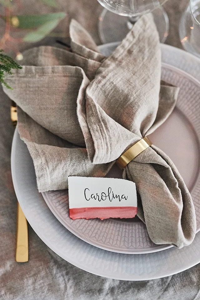 Ett tips för att vika servetter med servettring är att kombinera servettring i mässing med beige linneservett.