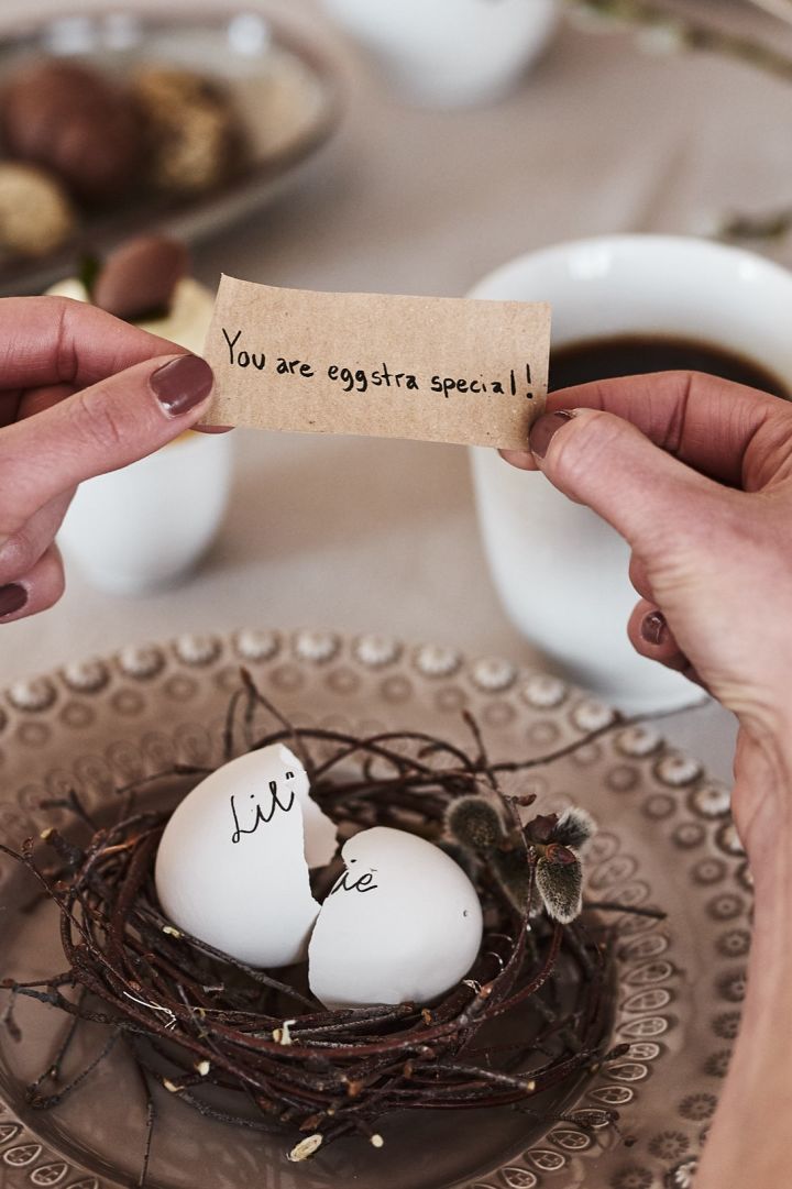 På tallrikskuvertet på påskdukningen har gästerna välkomnats med ett sött påskpyssel där ett fint meddelande gömts i ett urblåst ägg som bordsplacering.