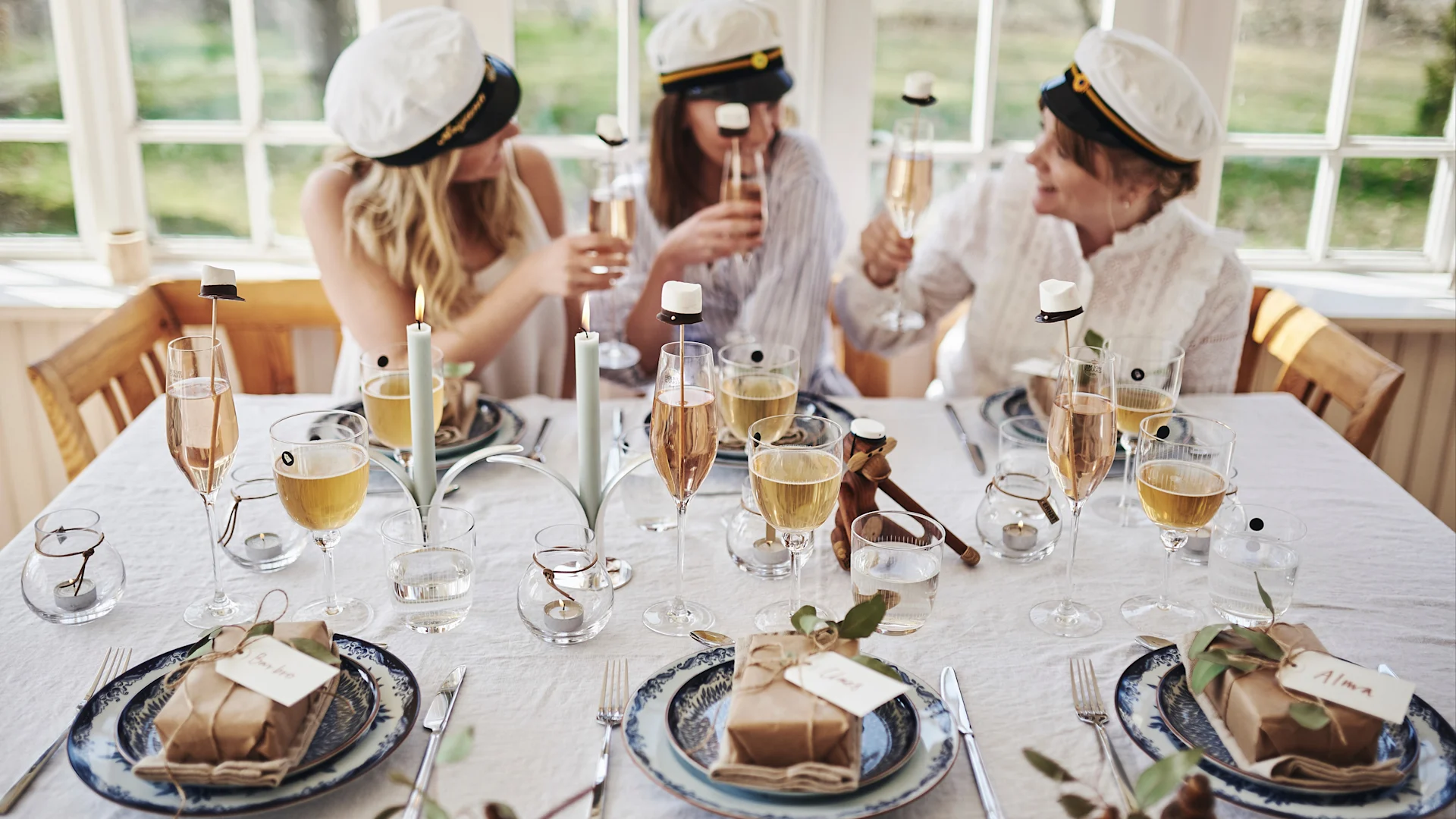 Studentfest med dukning i blåvitt och enkla dekorationer som studentmössor av marshmallows på pinne i glasen.