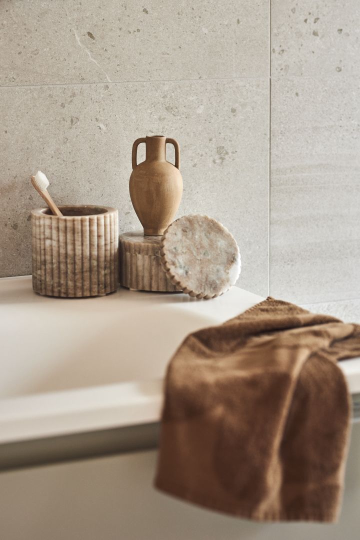 Kombinationen av olika material som keramik, linne och sten är en av höstens inredningstrender 2022. Här i ett badrum med dekorativa föremål. 
