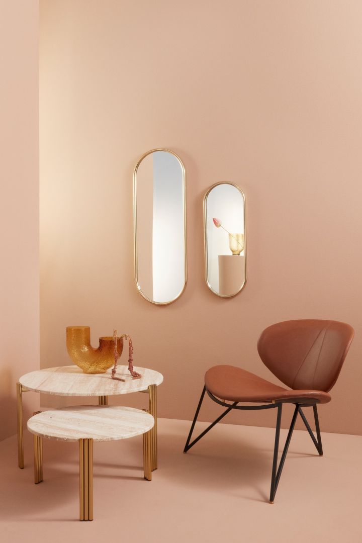 Stilfullt vardagsrum i persikotoner på väggarna, speglar med mässingkant och vacker läderfåtölj - alla aktuella tips inom inredning 2023.