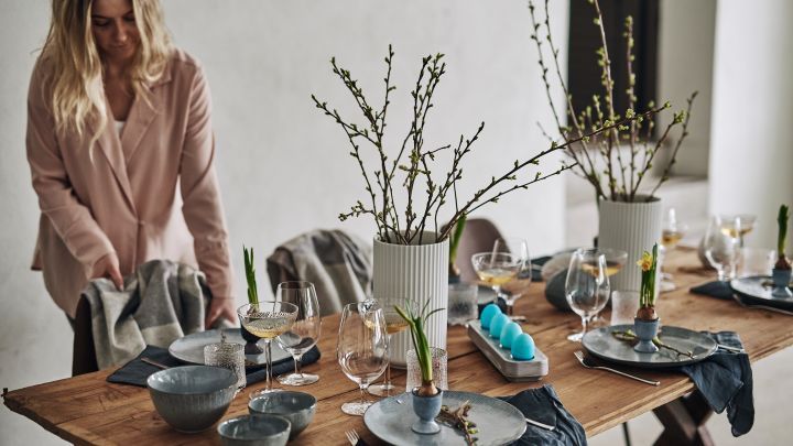 Tips för hur du kan duka i påsk med påskliljor på tallriken, färgade ägg på bordet och rustikt, blått porslin. 