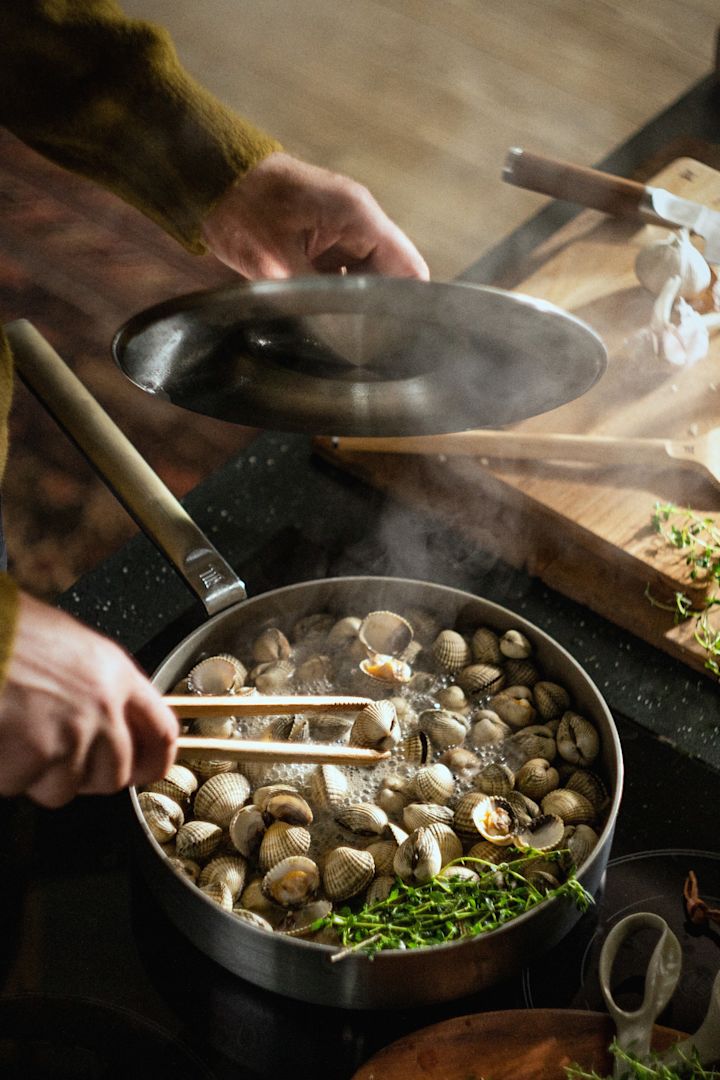 En person tillagar musslor i den rostfria sauterpannan Norden Steel från Fiskars.