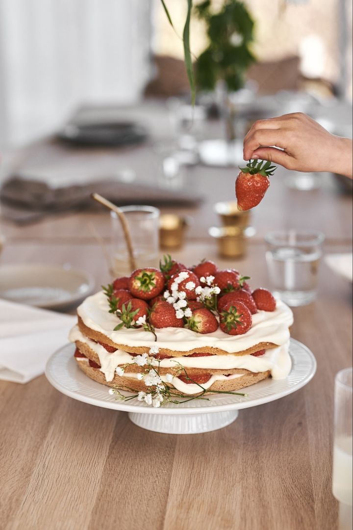 En enkel jordgubbstårta serverad på vitt tårtfat och dekorerad med brudslöja. 