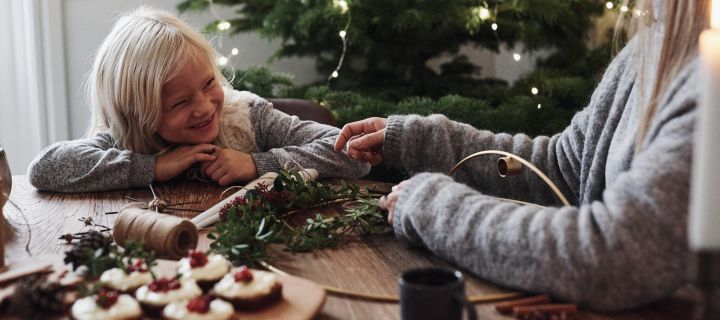 Mamma och barn testar olika julpyssel som att binda julkrans och njuter av en god julfika under tiden.