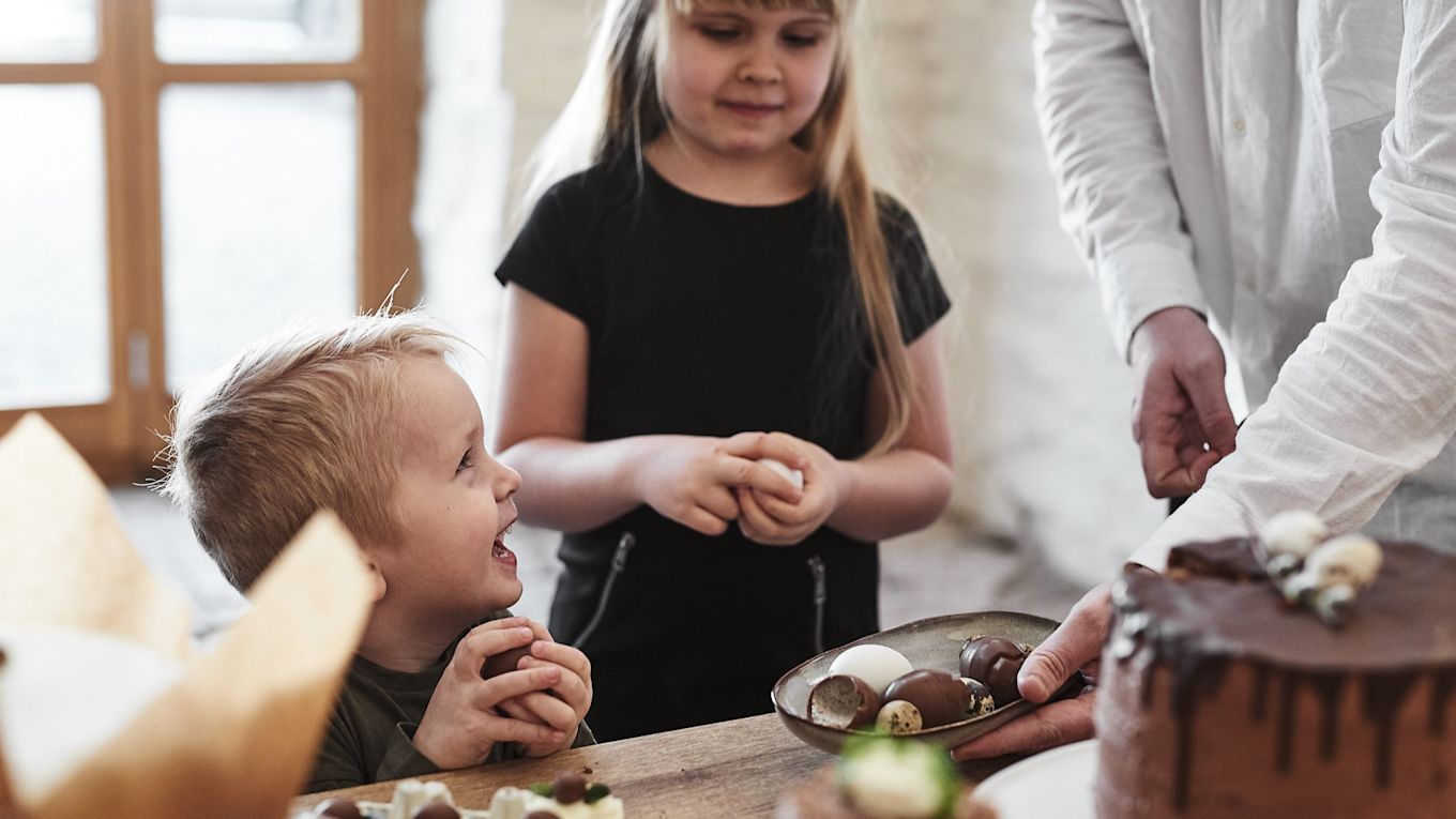 Ett dukat buffébord fyllt med desserter för en söt påskbuffé där chokladägg serveras ur ett rustikt serveringsfat från Bloomingville. 