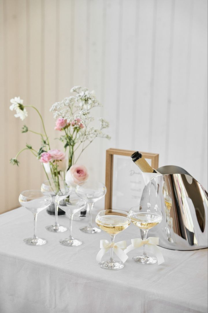Bröllop - tips, sätt upp ett bord med förfriskningar innan ceremonin som här med kupade champagneglas, en flaska bubbel och blommor på bordet.
