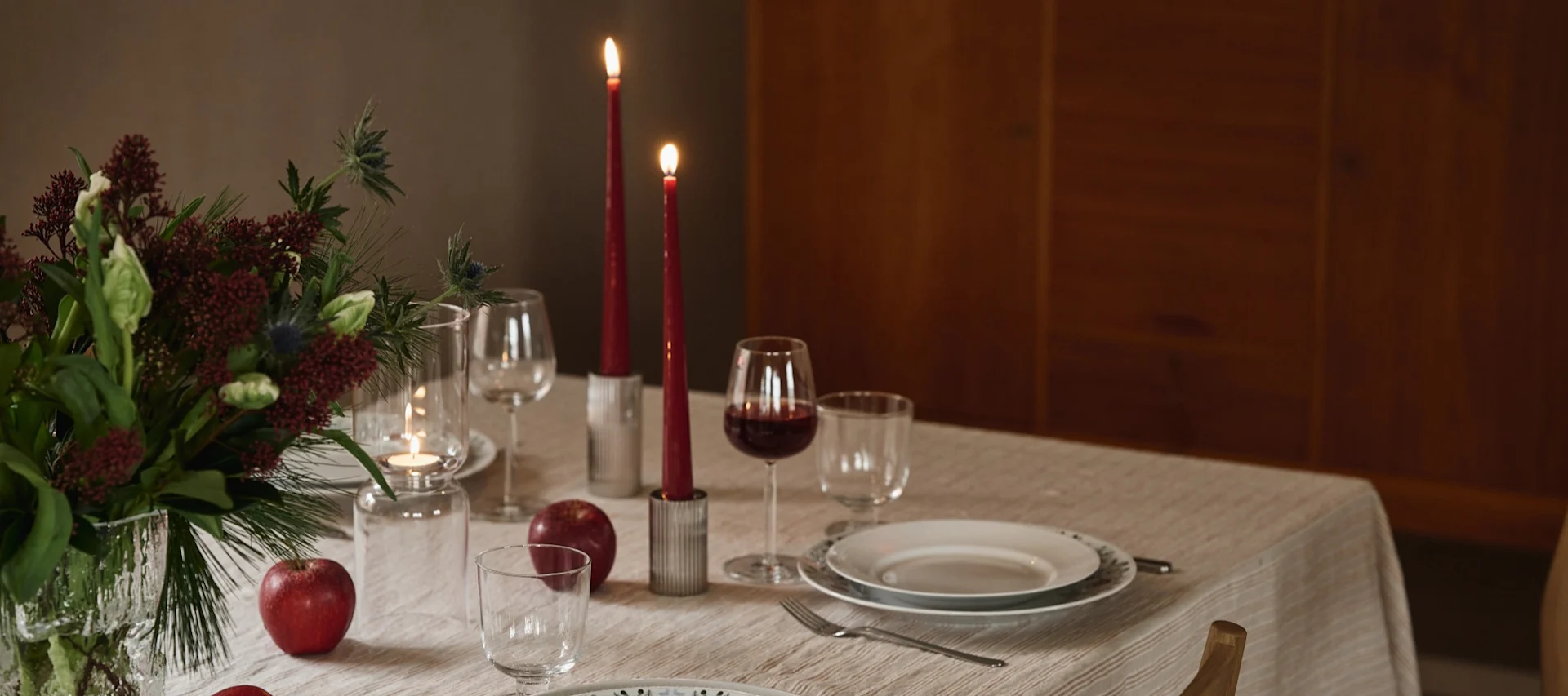 En juldukning 2025 med servis från Swedish Grace Winter, kompletterad med röda ljus och äpplen som dekorativa detaljer på bordet.
