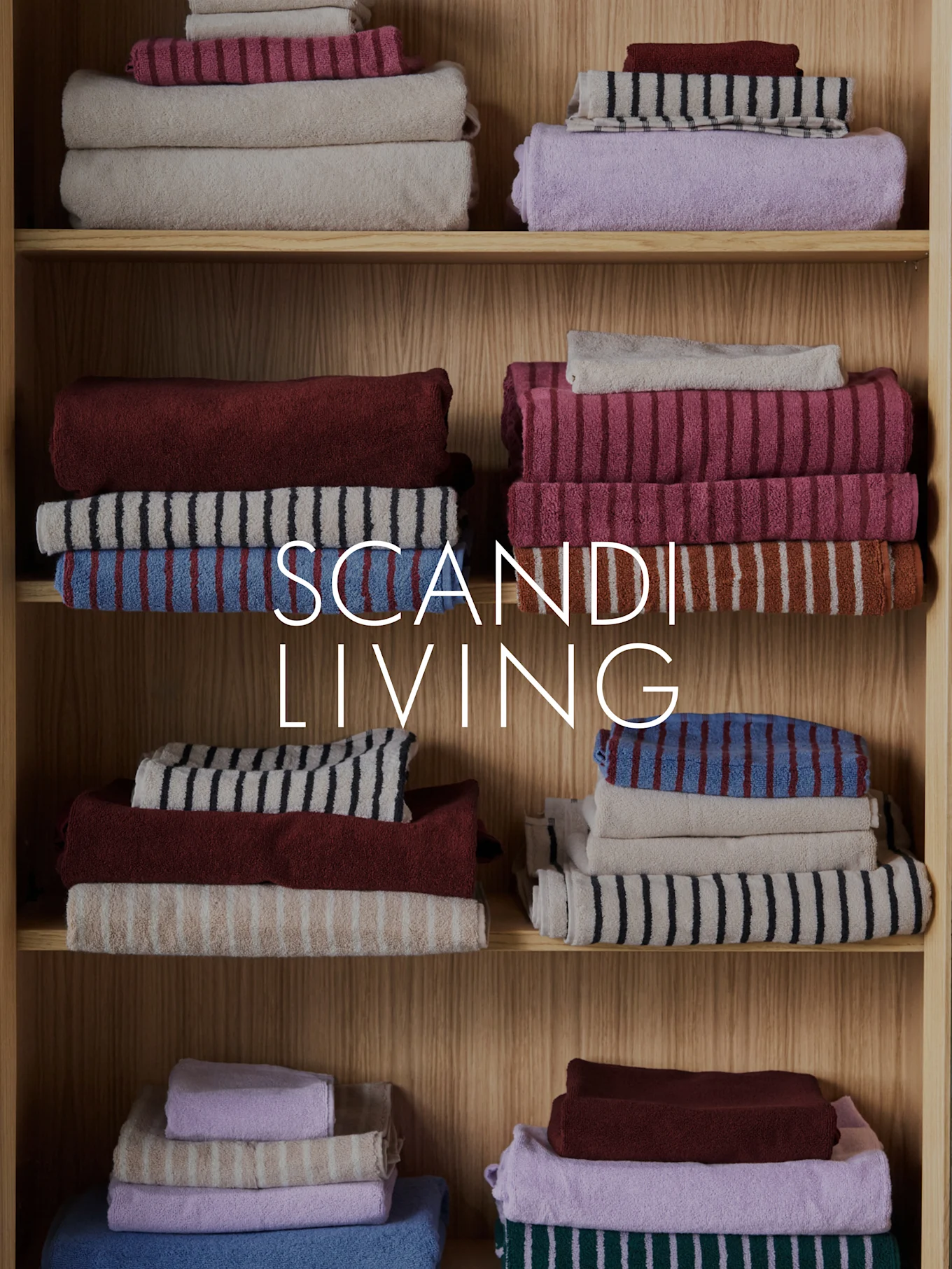 SCANDI LIVING text över staplade, vikta handdukar i olika färger och mönster på trähyllor.