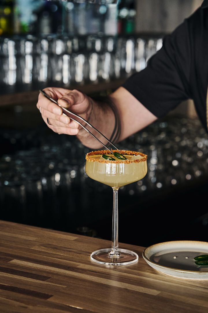 Perfekt för mocktails: cocktailglasen Essence från Iittala med drink, dekorerad kant och garnerade med jalapeñoskivor med hjälp av en tång.