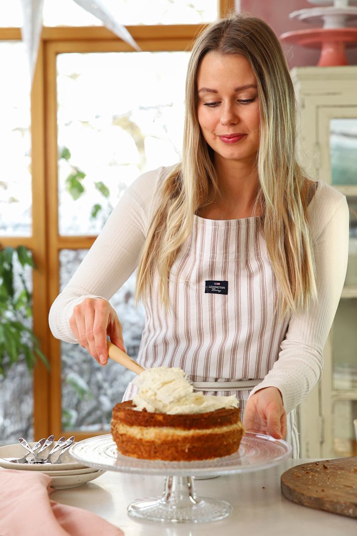 Baka med Frida till nyår – 3 festliga bakverk att bjuda på. Här sprider Frida Skattberg ut god grädde med Craft slickepott från Le Creuset på tårtan som står på Iittala Kastehelmi kakfat.