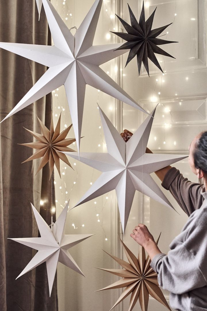 Julinredning med julstjärnor i papper som hänger från taket i ett hem. 