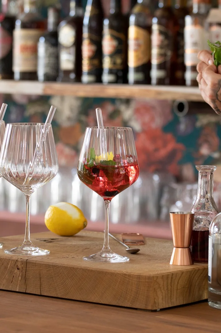 En mocktail i ett Feel Good G&T-glas från Nachtmann står på en träskiva framför en bar.