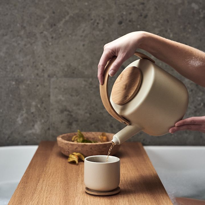 Kategoribild för vardagslyx - te hälls från Stelton tekanna i beigea toner och trä från badkaret.