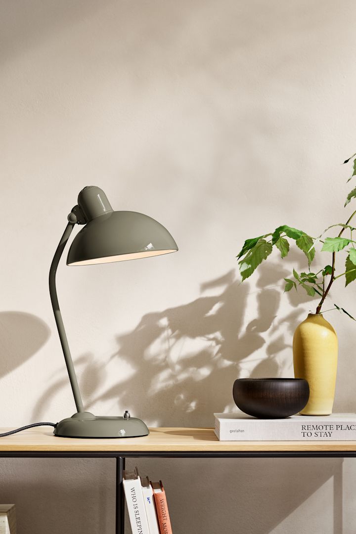 Bland inredningstrenderna för 2025 finns en naturlig nyans av olivgrönt, här ser du lampan från Fritz Hansen stående på ett sideboard. 