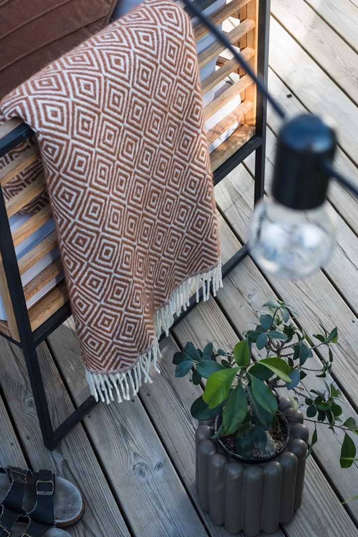Den bruna blomkrukan Mist från DBKD står på terrassen bredvid en bänk med en filt i @lindaz.se:s hem.