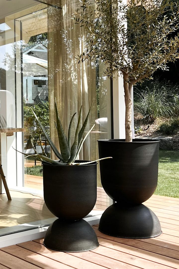 Bild som visar uteplats med två stora Hourglass-krukor i svart metall från Ferm Living.