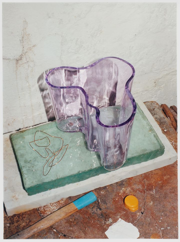 Alvar Aalto-vas från Iittala i en ljuslila nyans stående på stenblock.