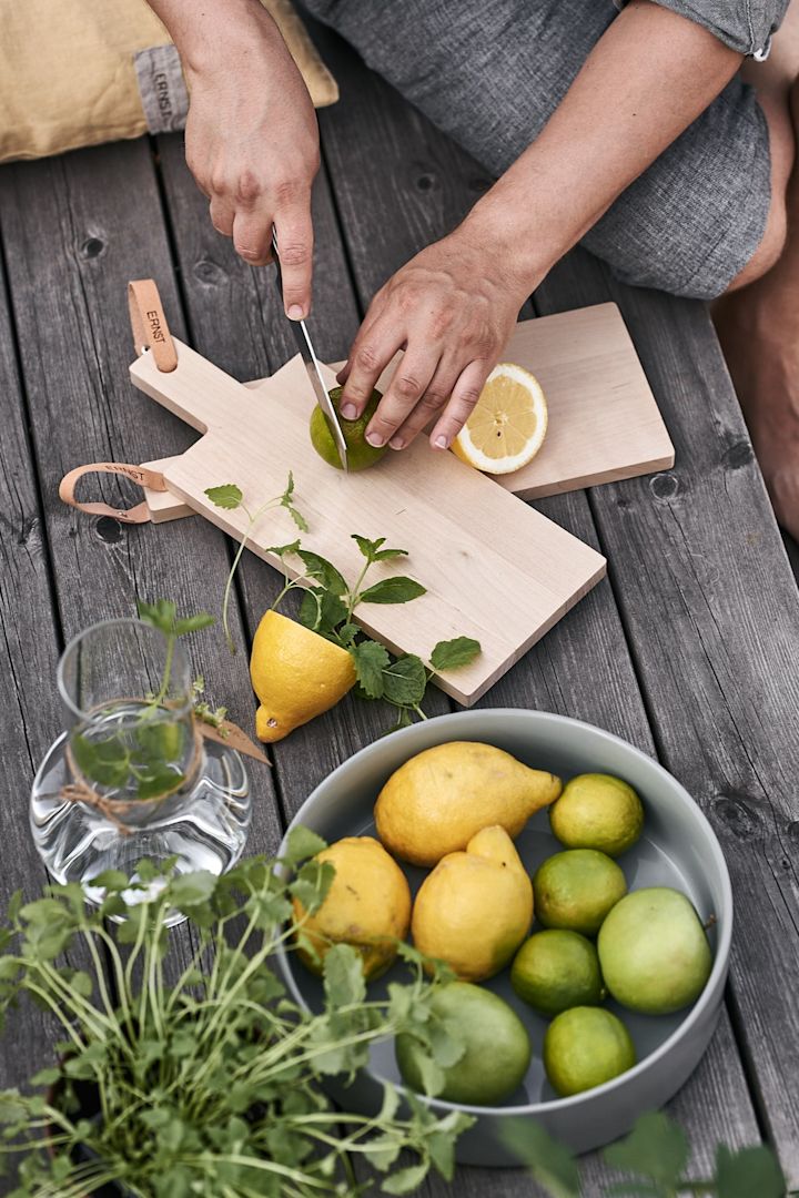 Dricka till sommarfesten förbereds på terrassen där det skivas citron och lime på skärbräda från ERNST.