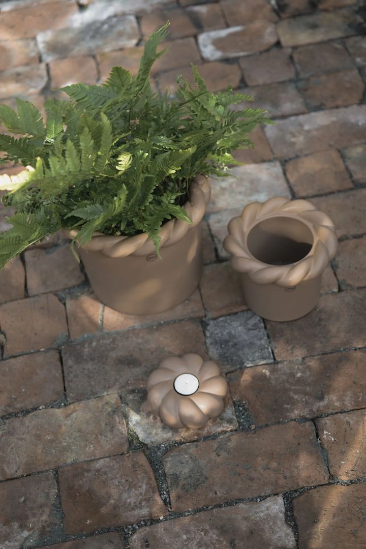 Twine krukor från DBKD har en modern design i stengods där krukorna har en bred flätad kant upptill vilket ger krukorna ett rustikt uttryck. Här två krukor i brunt bredvid varandra på stenlagd uteplats.