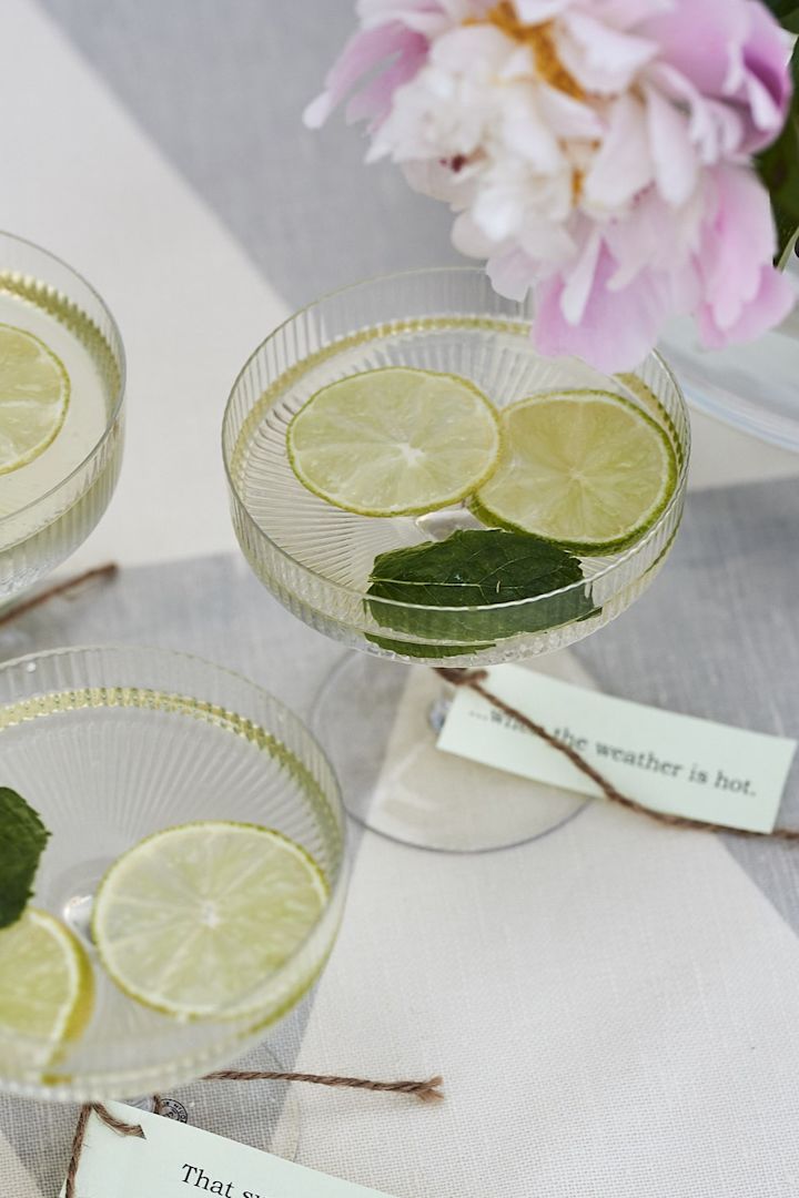 En svalkande sommardrink serveras på trädgårdsfesten ur kupade champagneglas från Ferm Living. 