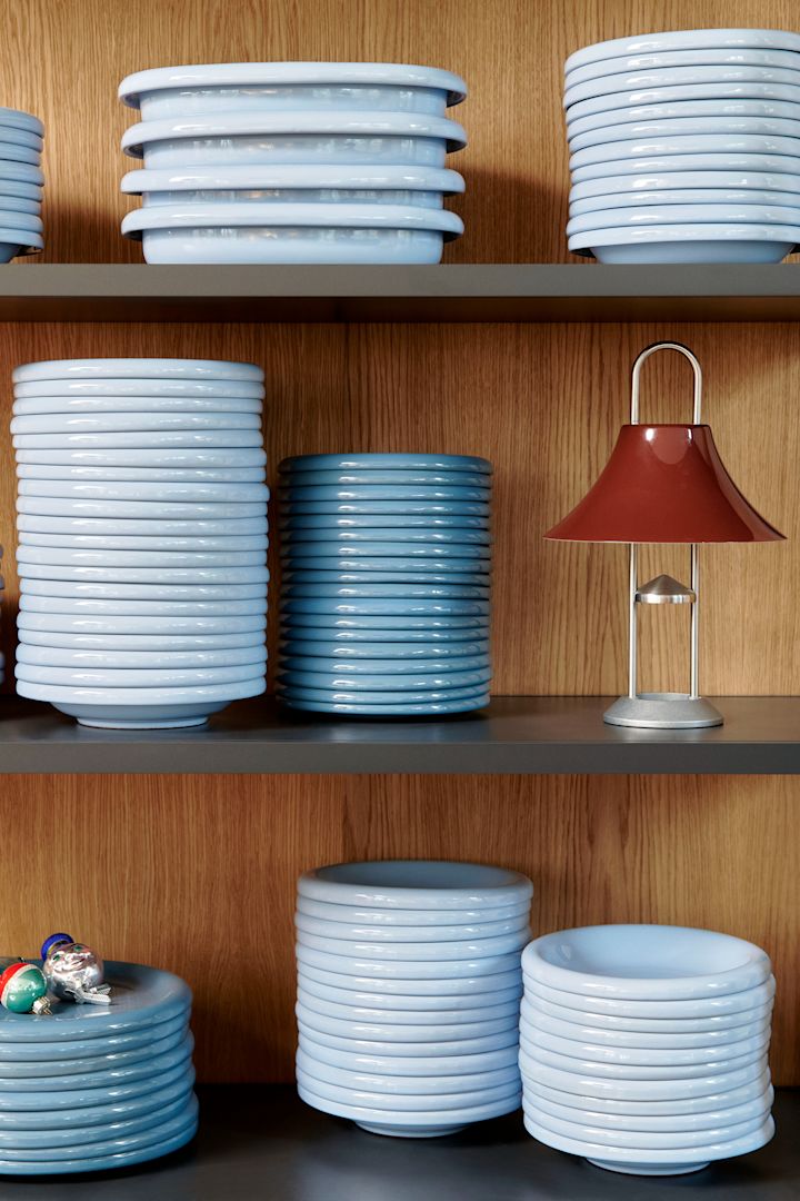 Himmelsblått är en viktig färg i Interior colour trends 2025. Här ser du en hög med barroplattor från Hay staplade i en trähylla. 